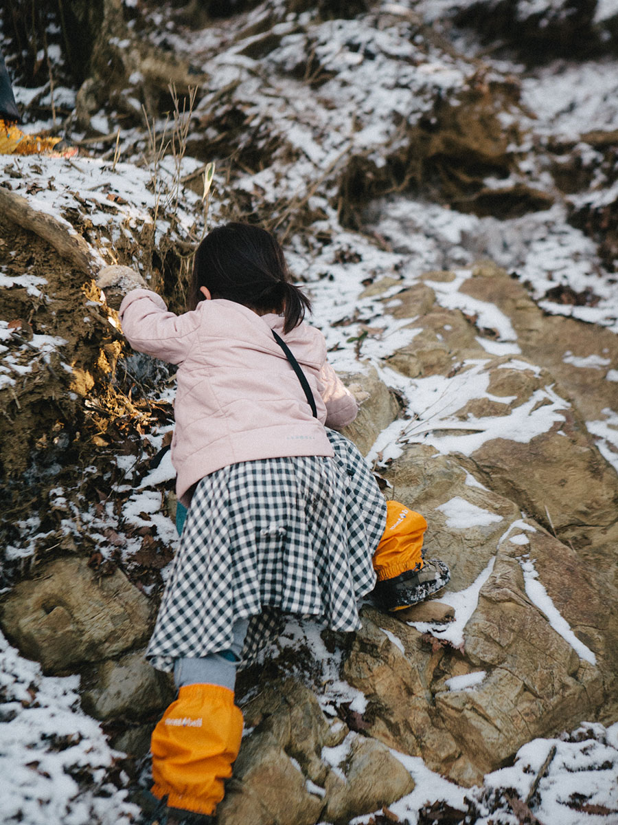 雪混じりの岩場を攀じ登る娘